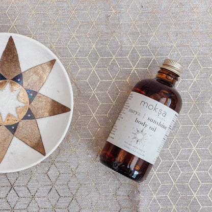 Bottle laying on its side on a printed table cloth next to a star plate.