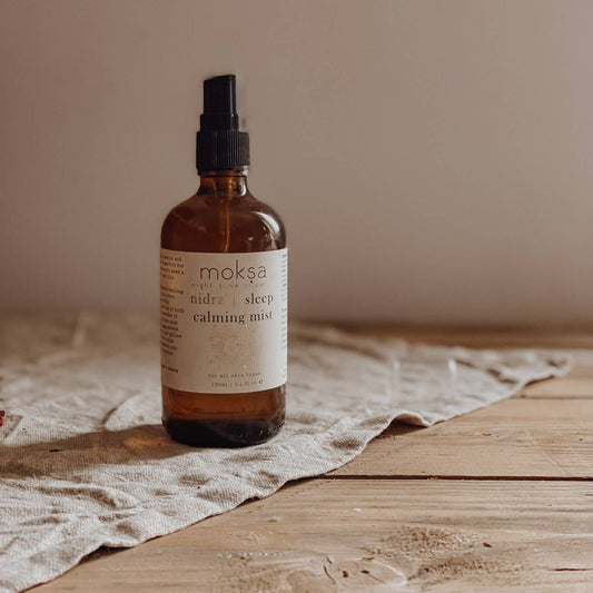 Bottle of mist sitting on a piece of cloth on a wooden table.
