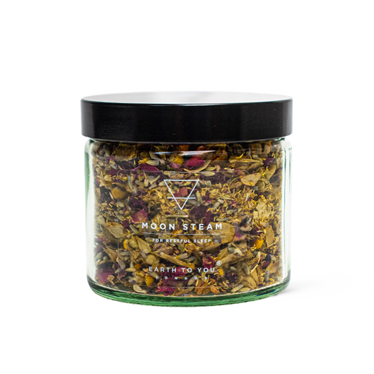 Glass jar with dried herbs labeled 'Moon Steam' on a white background