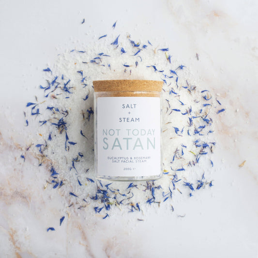 Jar of facial steam on a bed of the ingredients on a table.