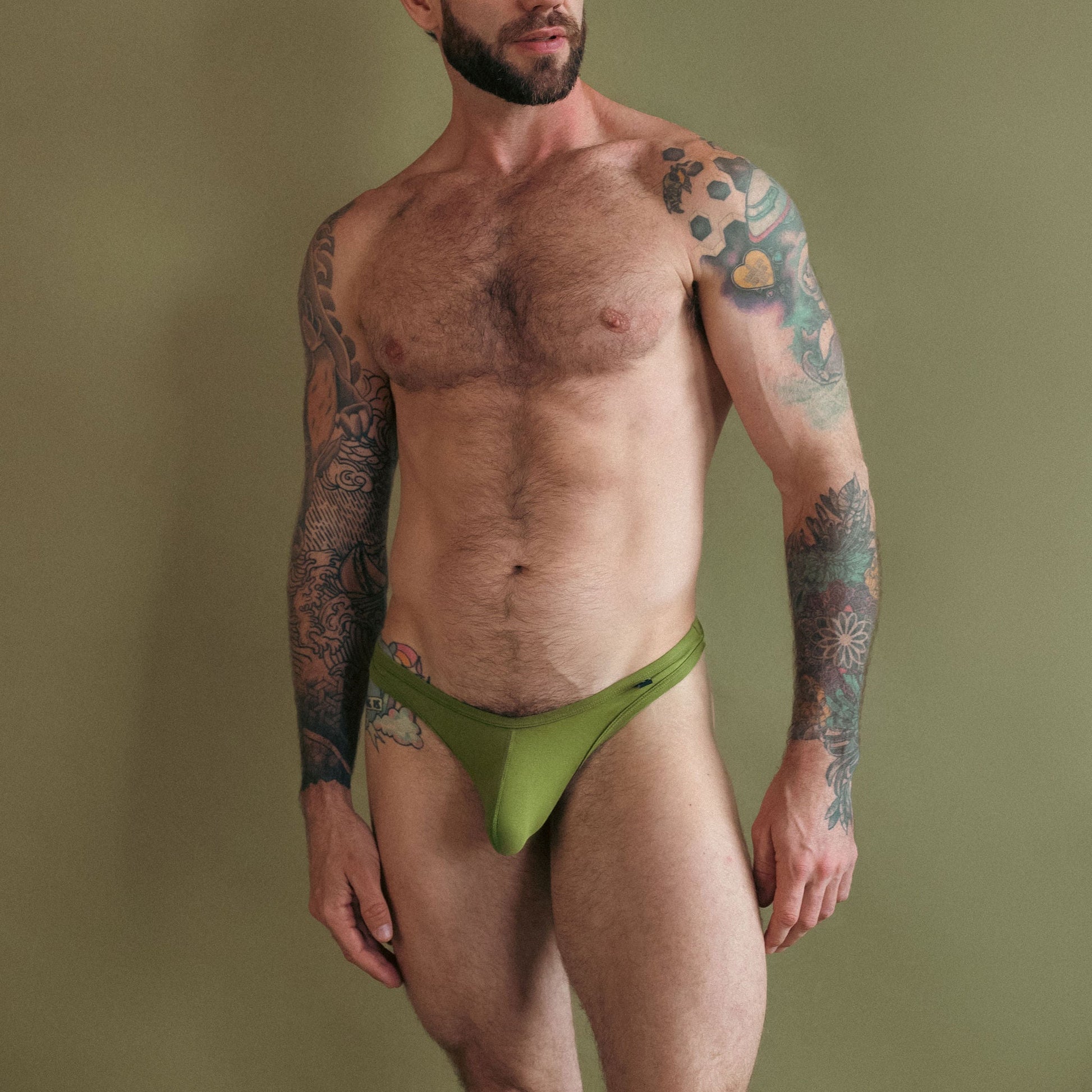 Man wearing a green thong against a plain background