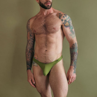 Man wearing a green thong against a plain background