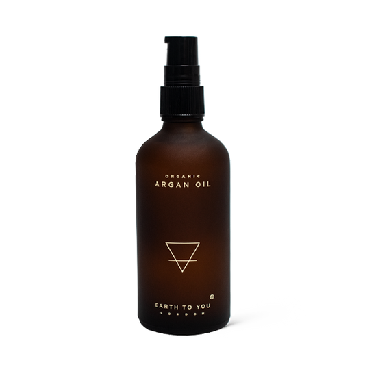 Brown bottle of organic argan oil with a black pump on a white background