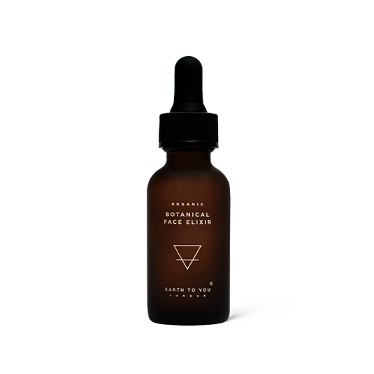Brown bottle of organic botanical face elixir with dropper on a white background