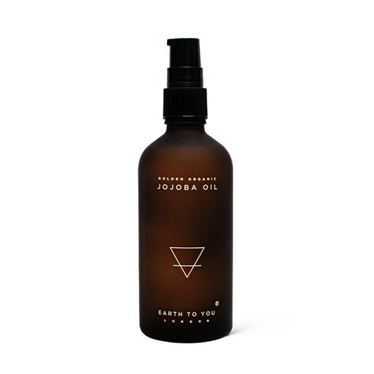 Brown bottle of Golden Organic Jojoba Oil with a black pump on a white background