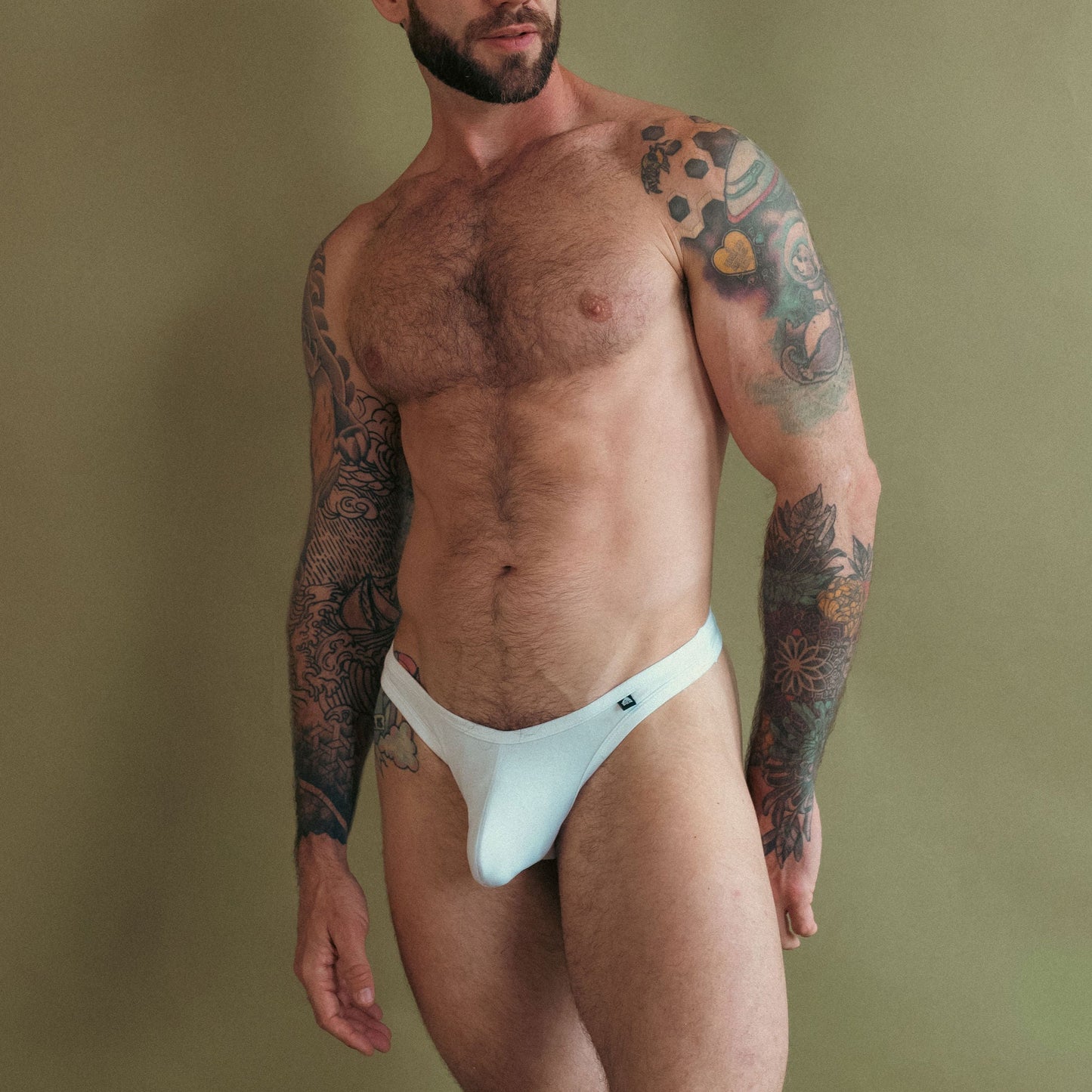 Man wearing a white thong against a plain background