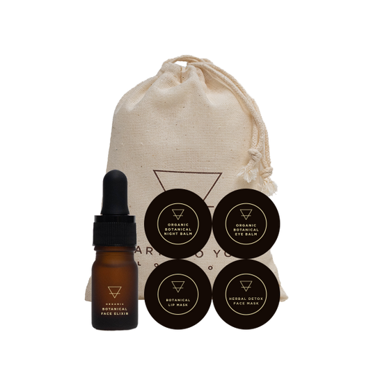 Skincare set with a dropper bottle, face mask, and lip balm in a drawstring bag on a white background