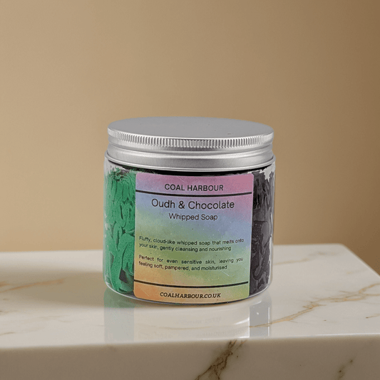 Jar of Coal Harbour Oudh & Chocolate Whipped Soap on a marble surface with a beige background