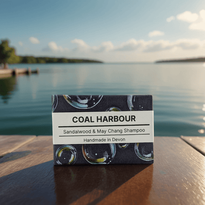 Coal Harbour Sandalwood & May Chang Shampoo bar packaging on a wooden surface with a lake in the background